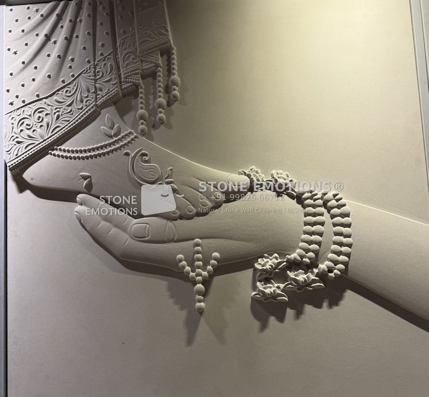 Close-up natural stone relief of a hand cradling an adorned foot with an anklet and garment border
